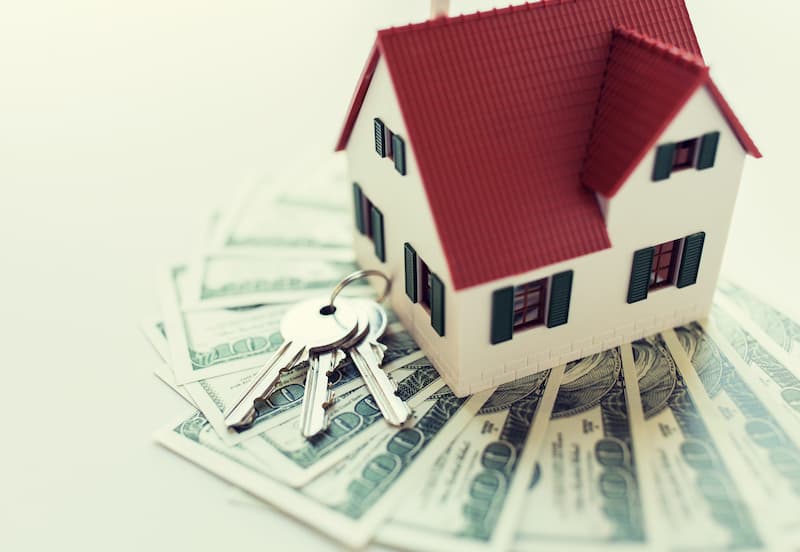 Affordable moving and living. mini house on a set of keys and money.