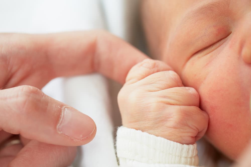 baby hand holding onto an adult index finger