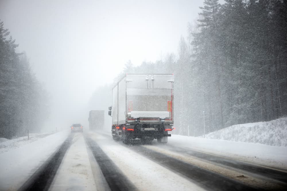 Winter moving truck travelling down a snow filled road.